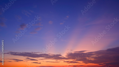 Dramatic Evening Sky Background with Majestic orange sunlight and clouds on dark blue Twilight sky in widescreen view