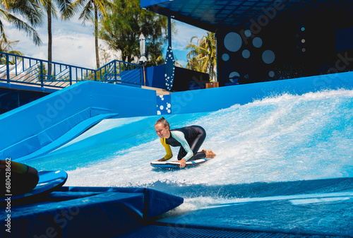 Photography Beautiful young woman surfing on a wave simulator at a water amusement park