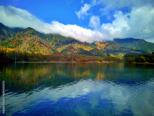 Beautiful Taisho Pond at Kamikochi, Japan. The still blue waters of the pond reflect the surrounding forested mountains.