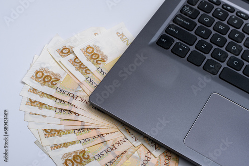 Plik polskich banknotów pln leży obok komputera laptopa