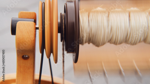 Close-up of a spinning loom with thread in the background The spinning wheel with its intricate design is a popular choice for hobbyists and craft enthusiasts
