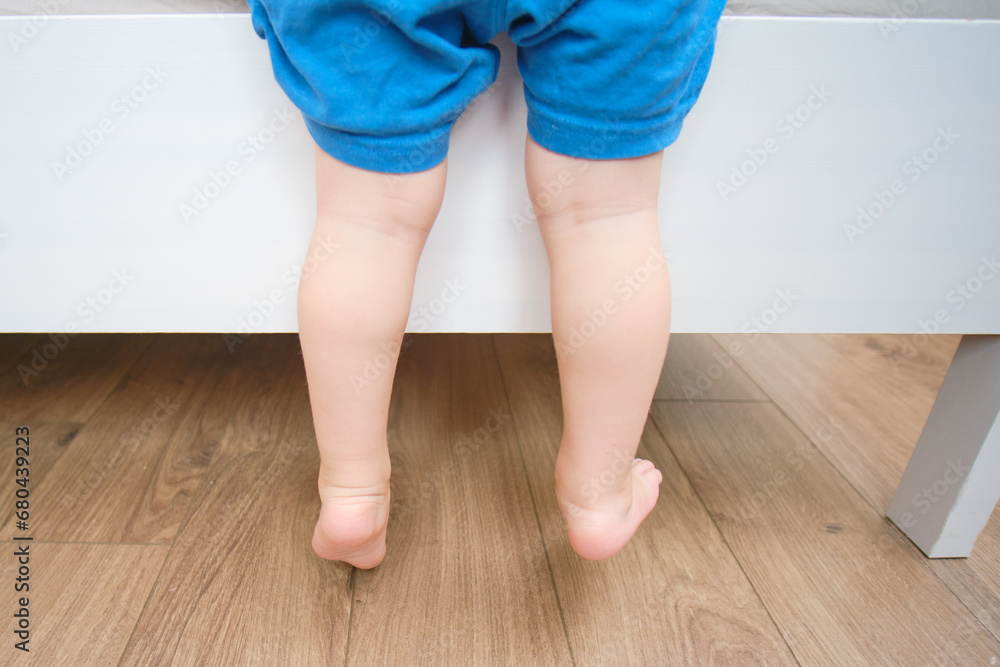 Baby is climbing on the edge of the bed, there's a risk of an indoor accident. Kid aged two years (two-year-old boy) Baby is climbing on the edge of the bed, there's a risk of an indoor accident. Kid aged two years (two-year-old boy)