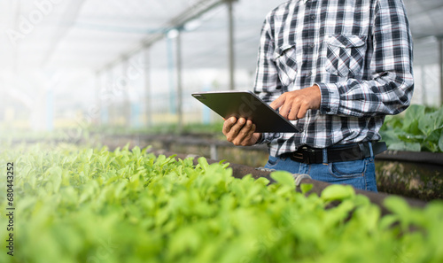 Asian farmer using digital tablet inspecting fresh vegetable in organic farm. Agriculture technology