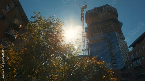 Tracking shot of a large building of office suites in construction against a bright blue sky in London, England, UK photo