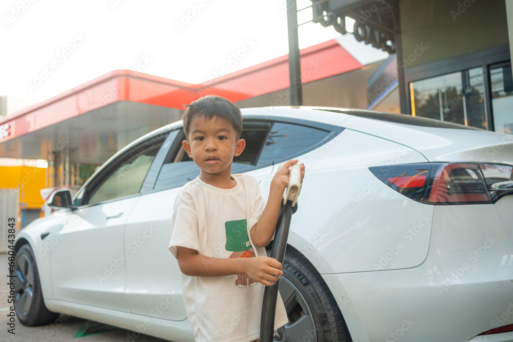 Little boy use EV car charge on electric car station vacation trip