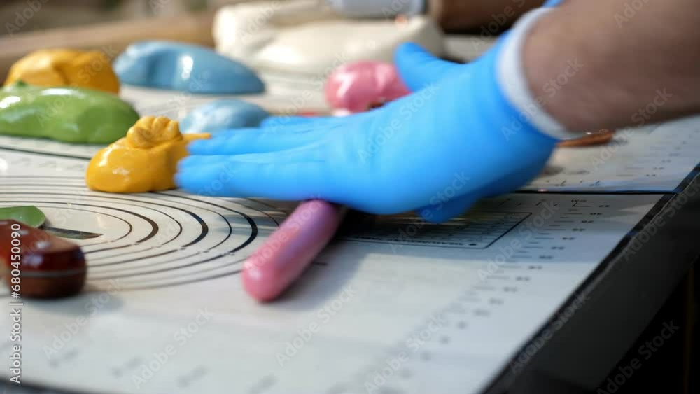 Close-up of the creation of multi-colored caramel candies, the pastry chef rolls out soft colored caramel creating lollipops of various shapes. Close-up of the creation of multi-colored caramel candies, the pastry chef rolls out soft colored caramel creating lollipops of various shapes.