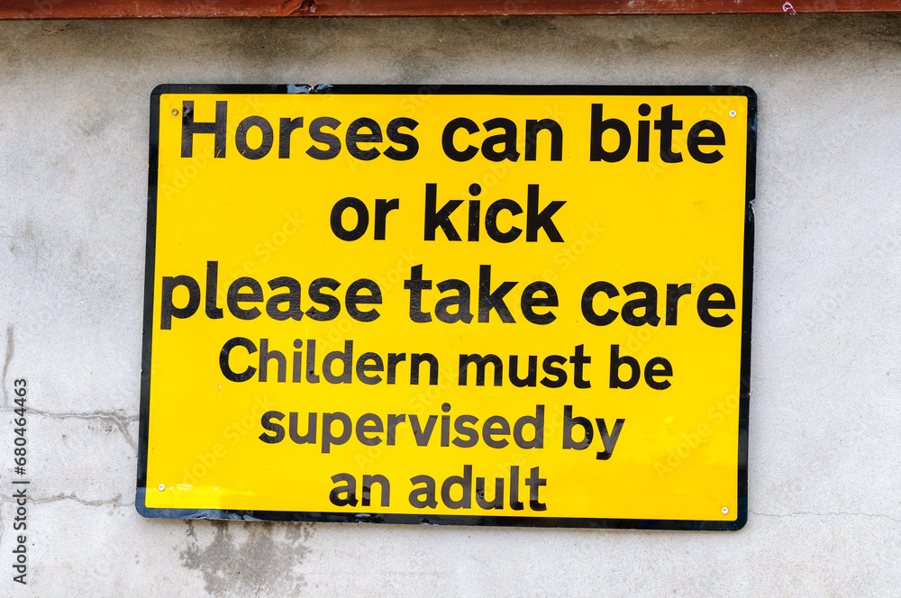 AA Street sign warning that horses can kick and bite, and advising children should be accompanied (mis-spelt as 