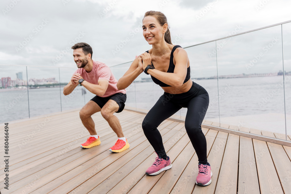 Fitness sports woman and man in sportswear in summer. Friends are sports people doing exercises, warming up before the start of training.