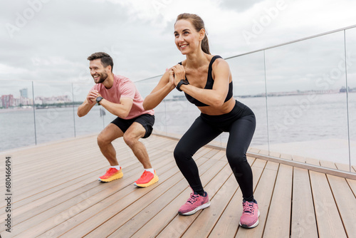 Fitness sports woman and man in sportswear in summer. Friends are sports people doing exercises  warming up before the start of training.