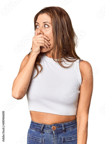 Middle-aged woman portrait in studio setting thoughtful looking to a copy space covering mouth with hand.