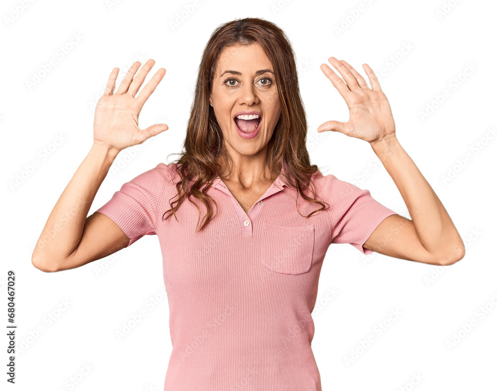 Middle-aged woman portrait in studio setting receiving a pleasant surprise, excited and raising hands. Middle-aged woman portrait in studio setting receiving a pleasant surprise, excited and raising hands.