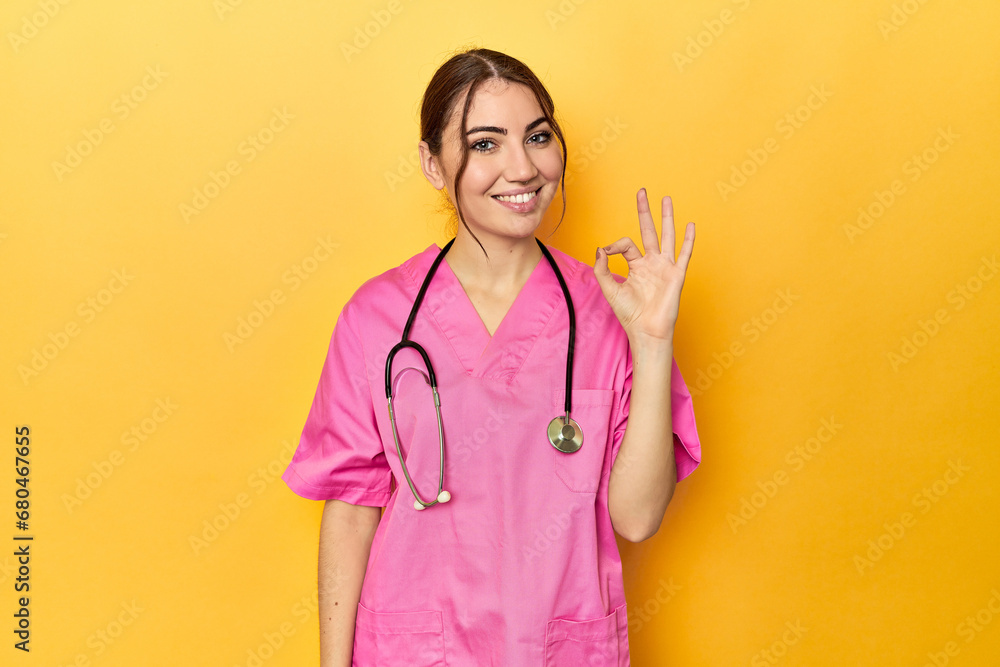 Nursing assistant in yellow background cheerful and confident showing ok gesture. Nursing assistant in yellow background cheerful and confident showing ok gesture.