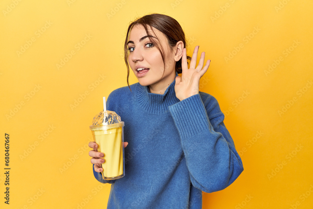 Young caucasian woman enjoying a creamy vanilla shake trying to listening a gossip. Young caucasian woman enjoying a creamy vanilla shake trying to listening a gossip.