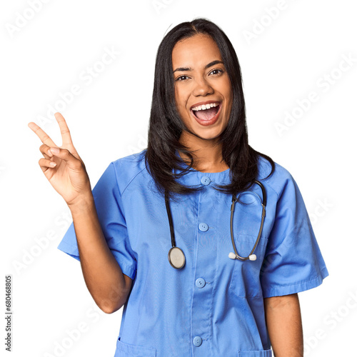 Young Filipina nurse posed in studio joyful and carefree showing a peace symbol with fingers.