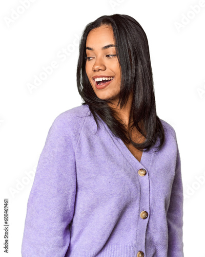 Young Filipina with long black hair in studio looks aside smiling, cheerful and pleasant.