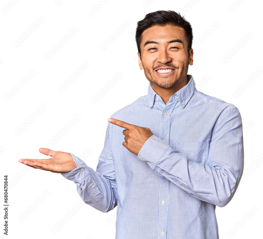 Young Chinese man in studio background excited holding a copy space on palm. Young Chinese man in studio background excited holding a copy space on palm.