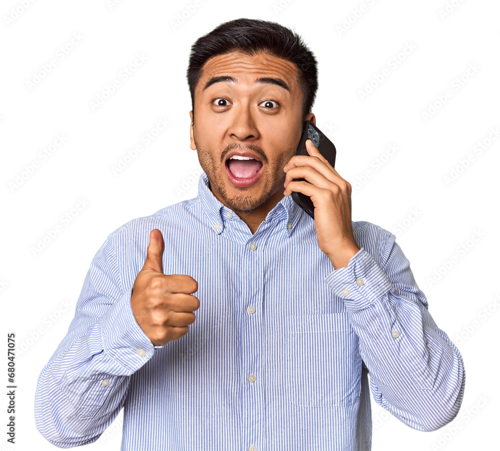 Euphoric Chinese man on phone celebrating news in studio Euphoric Chinese man on phone celebrating news in studio