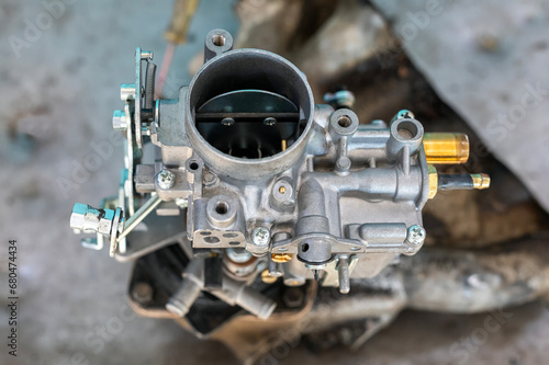 View of automobile carburetor. A carburetor (also spelled carburettor or carburetter) is a device used by a gasoline internal combustion engine to control and mix air and fuel entering the engine. photo