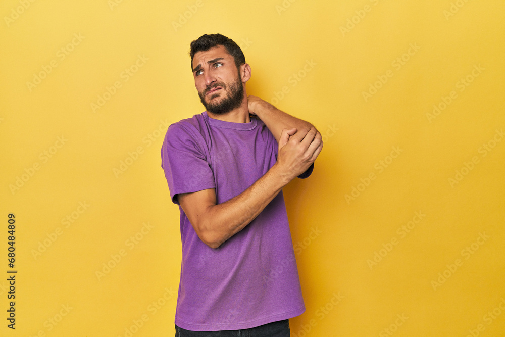 Young Hispanic man on yellow background massaging elbow, suffering after a bad movement. Young Hispanic man on yellow background massaging elbow, suffering after a bad movement.