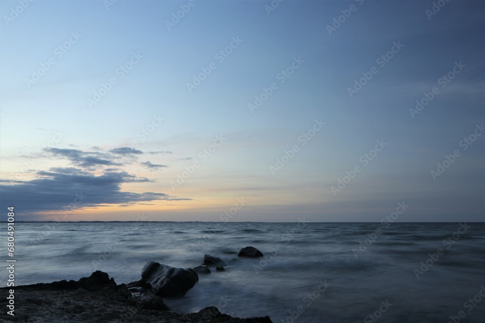 Smooth seascape with rocks at dusk.