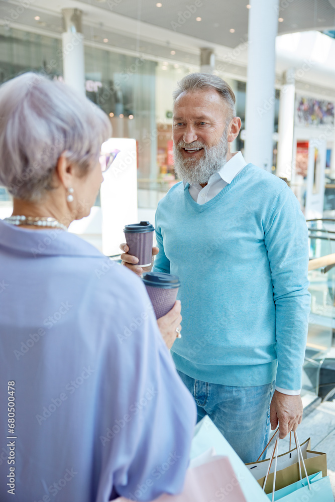 Obraz premium Stylish senior couple drinking coffee taking break during shopping in mall