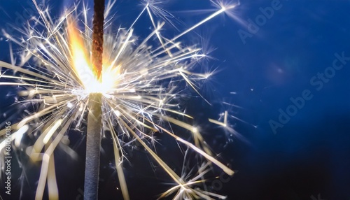 Sparkler burning bright with shiny sparks. Dark blue festive background. Happy New Year concept.