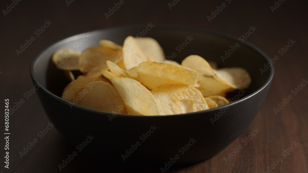 potato chips in black bowl on wood table potato chips in black bowl on wood table