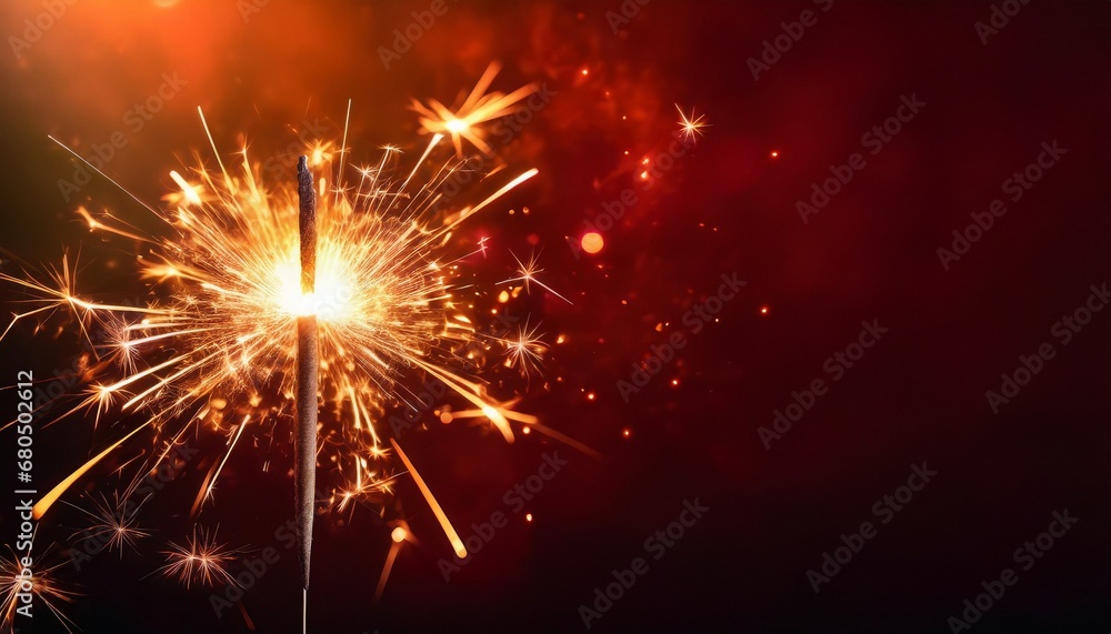 Sparkler burning bright with shiny sparks. Dark red festive background. Happy New Year concept.