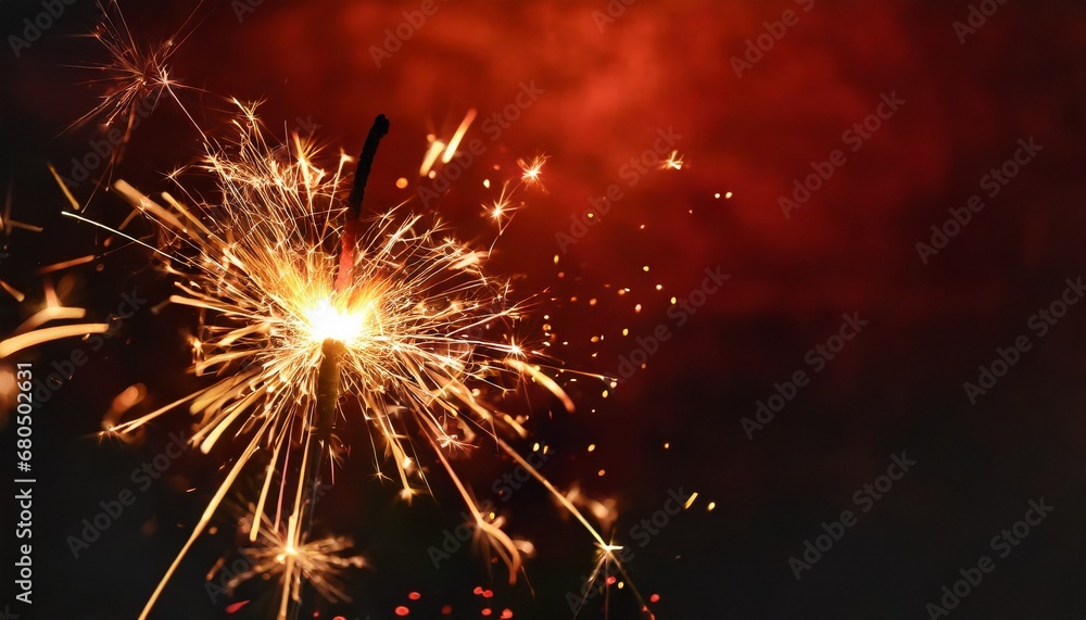 Sparkler burning bright with shiny sparks. Dark red festive background. Happy New Year concept.