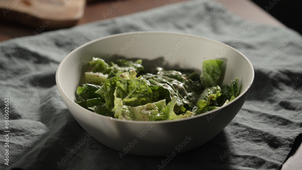 man mixing dressing over romaine leaves in white bowl man mixing dressing over romaine leaves in white bowl