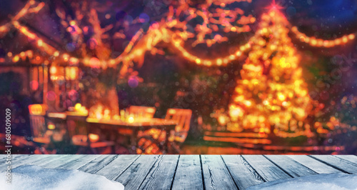 wooden table and winter christmas tree illuminated, party in backyard garden with grill BBQ, blurred background