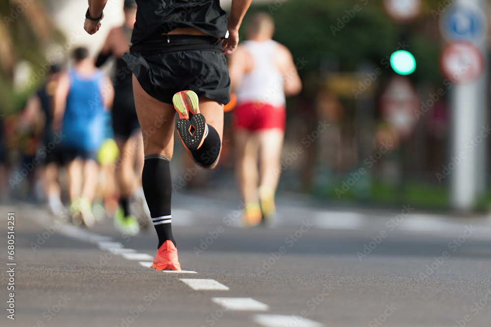 Marathon runners running on city road, large group of runners, close-up legs runners running sport marathon, male jogging race in asphalt road, athletics competition