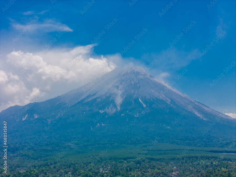 Aerial view of Semeru mountain, blue cloudy sky and jungle near Tumpak Sewu Waterfall in Java in East Java, Indonesia