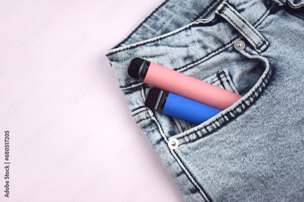 A set of multi-color disposable electronic cigarettes in a jeans pocket.