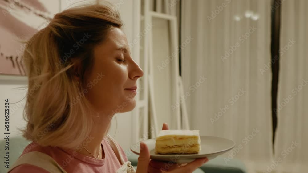 Happy pregnant woman smells sweet cake in anticipation of eating it. Pregnant female enjoying sweet dessert cake sitting in the living room. Happy pregnant woman smells sweet cake in anticipation of eating it. Pregnant female enjoying sweet dessert cake sitting in the living room.