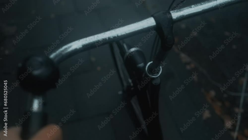 Young man rides a bicycle along the road on a rainy day. A view from the first person to the steering wheel, hand and road. Young man rides a bicycle along the road on a rainy day. A view from the first person to the steering wheel, hand and road.