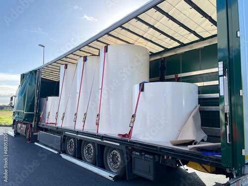 Loading, transporting and unloading large rolls of paper in a semi-trailer. Securing cargo with straps and locks for stability