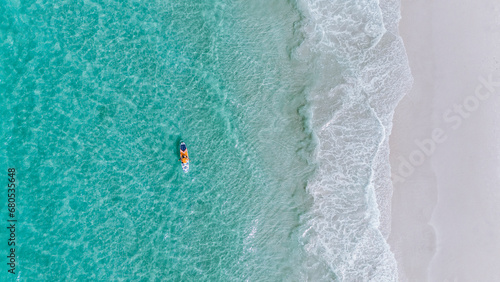 overhead drone view of a person on his stand up paddle board in the sea with green water on the beach with the whitest sand in the world in Jervis Bay, Australia on a daylight morning on vacation photo