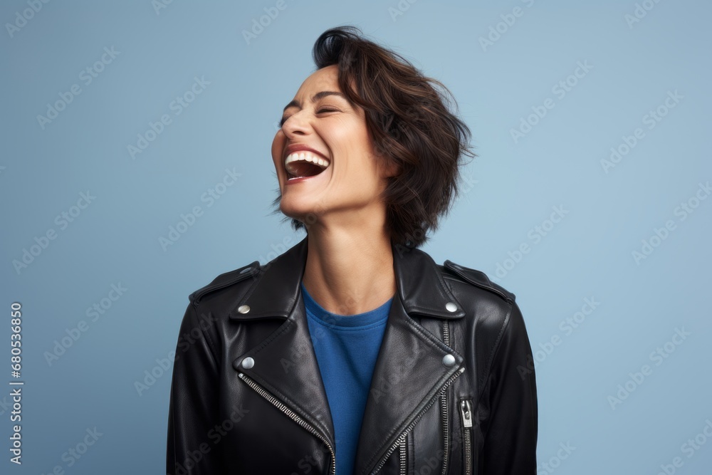 Portrait of a joyful woman in her 40s sporting a classic leather jacket against a soft blue background. AI Generation Portrait of a joyful woman in her 40s sporting a classic leather jacket against a soft blue background. AI Generation