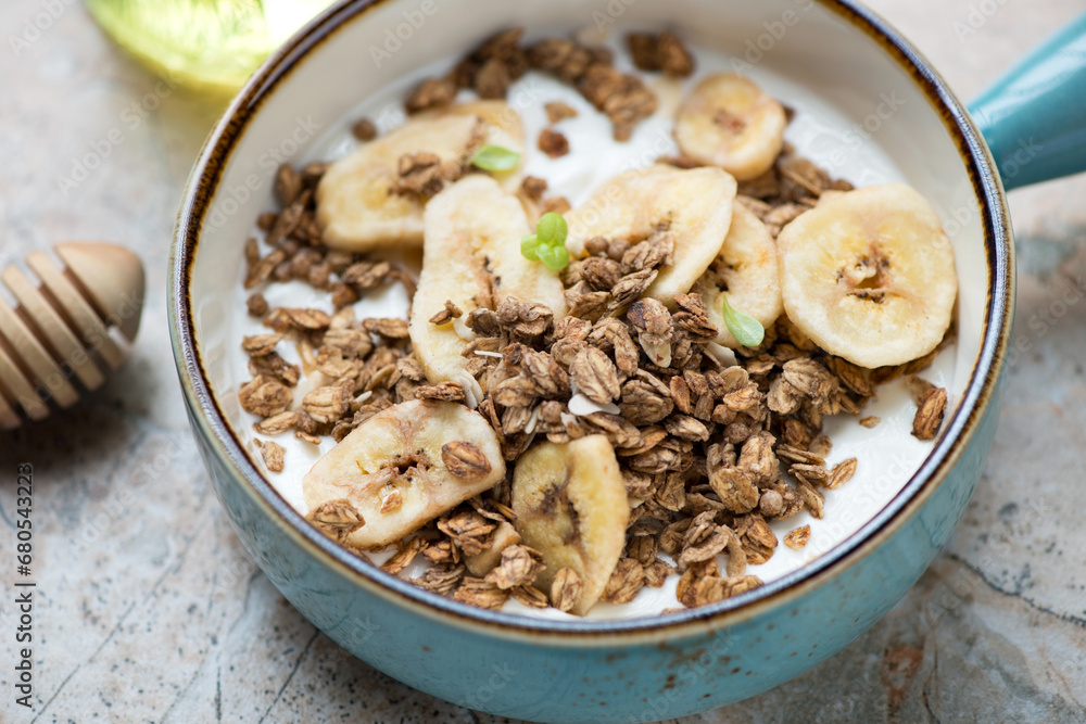 Turquoise serving bowl with greek yogurt, granola and banana chips, close-up, horizontal shot, selective focus Turquoise serving bowl with greek yogurt, granola and banana chips, close-up, horizontal shot, selective focus