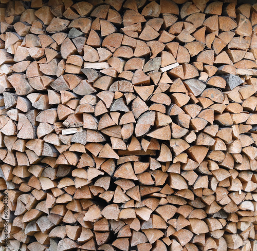 Firewood stacked near the wooden wall of old hut. Many chopped logs of firewood close up