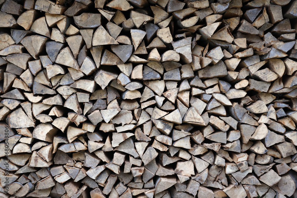 Firewood stacked near the wooden wall of old hut. Many chopped logs of firewood close up Firewood stacked near the wooden wall of old hut. Many chopped logs of firewood close up