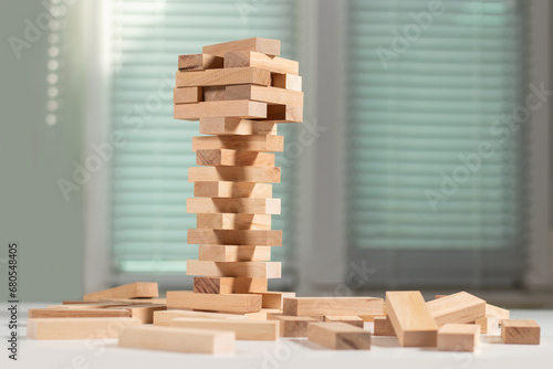 Board game Jenga Tower made of wooden blocks. A tower of unevenly shifted wooden beams. photo