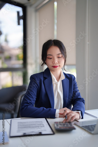 Businesswomen checking finance data on document and finance chart on digital laptop with calculator while working to analysis strategy investment and management about new startup project in workplace