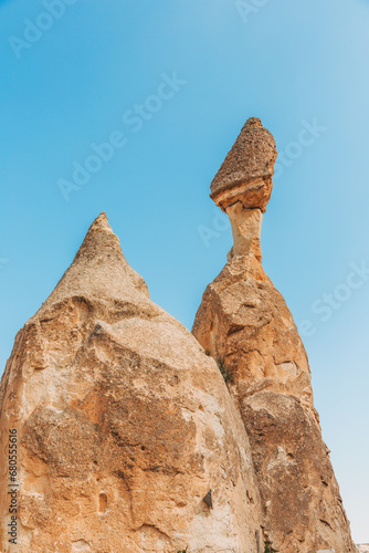 Against a clear blue sky, the unique rock formations known as fairy chimneys stand tall in Cappadocia, Turkey, showcasing nature's sculptural artistry crafted by centuries of erosion.