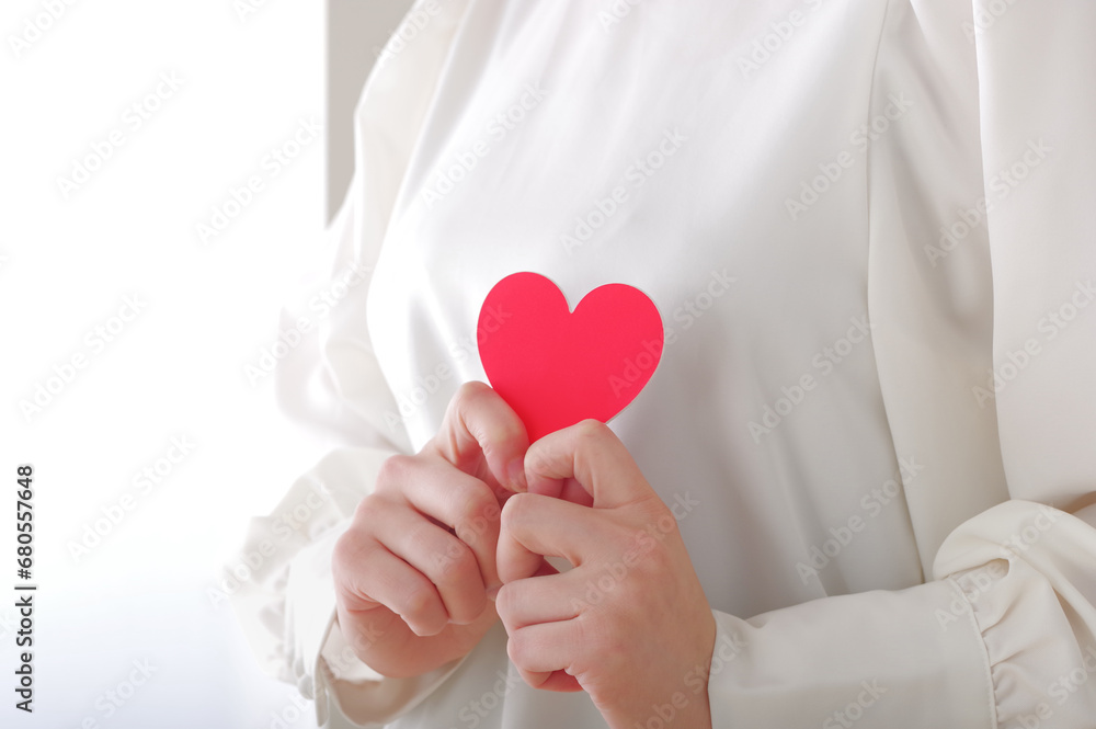 胸元でハートのオブジェを持つ女性