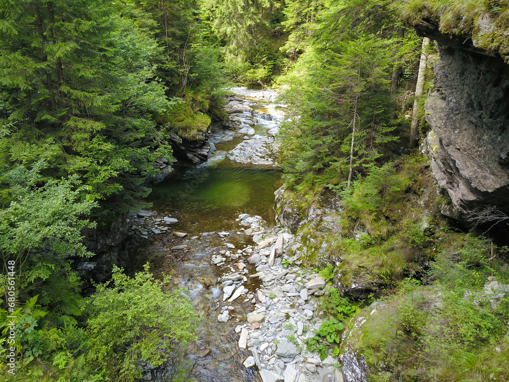 Drone panorama above a rapid mountain river forming stepped cascades and a pond when flowing through eroded large stone pieces. Latorita Mountains, Carpathia, Romania. Drone panorama above a rapid mountain river forming stepped cascades and a pond when flowing through eroded large stone pieces. Latorita Mountains, Carpathia, Romania.