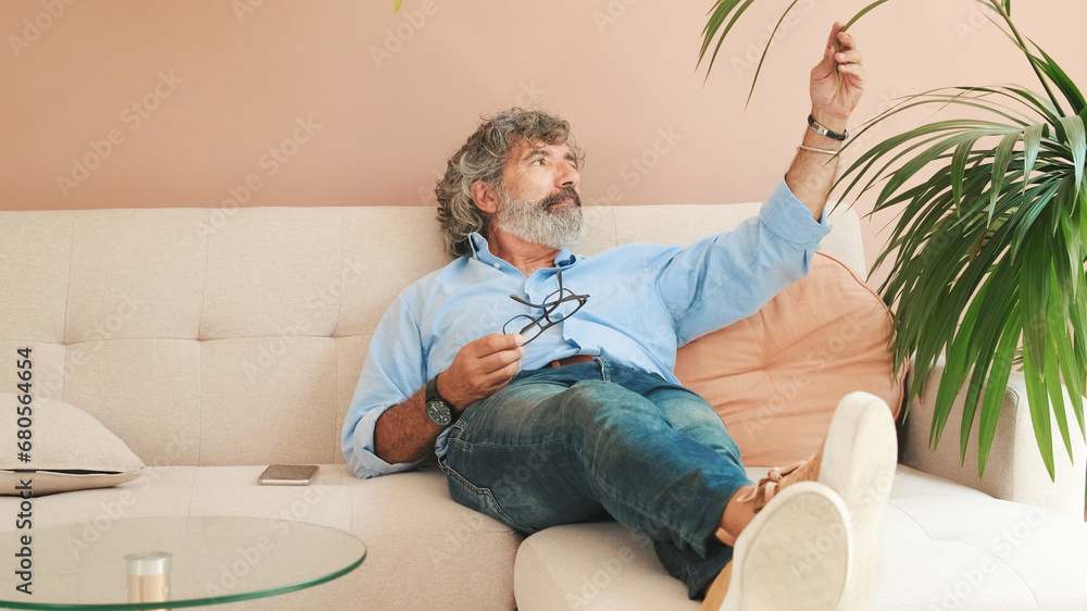 An elderly man is resting lying on the sofa in cozy living-room