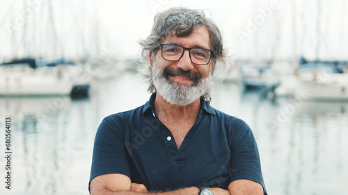 Konstfotografi Happy male seigneur in glasses crossing his arms while standing in the port and