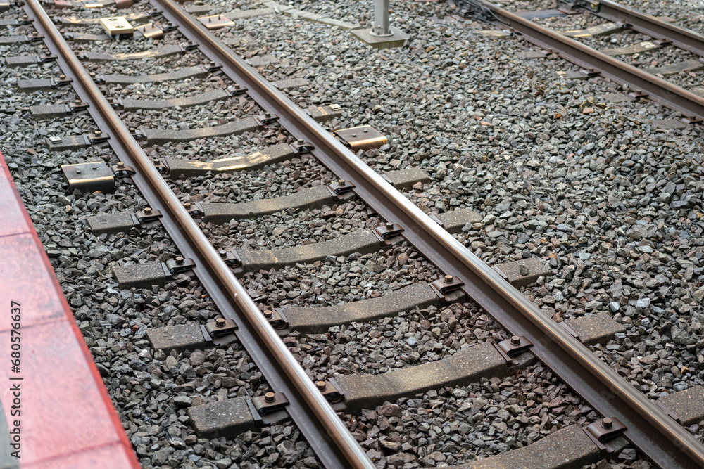 Streel train track railway on the gravel rock ground at the local station platform. Transporatation system and equipment object photo. Selective focus. Streel train track railway on the gravel rock ground at the local station platform. Transporatation system and equipment object photo. Selective focus.